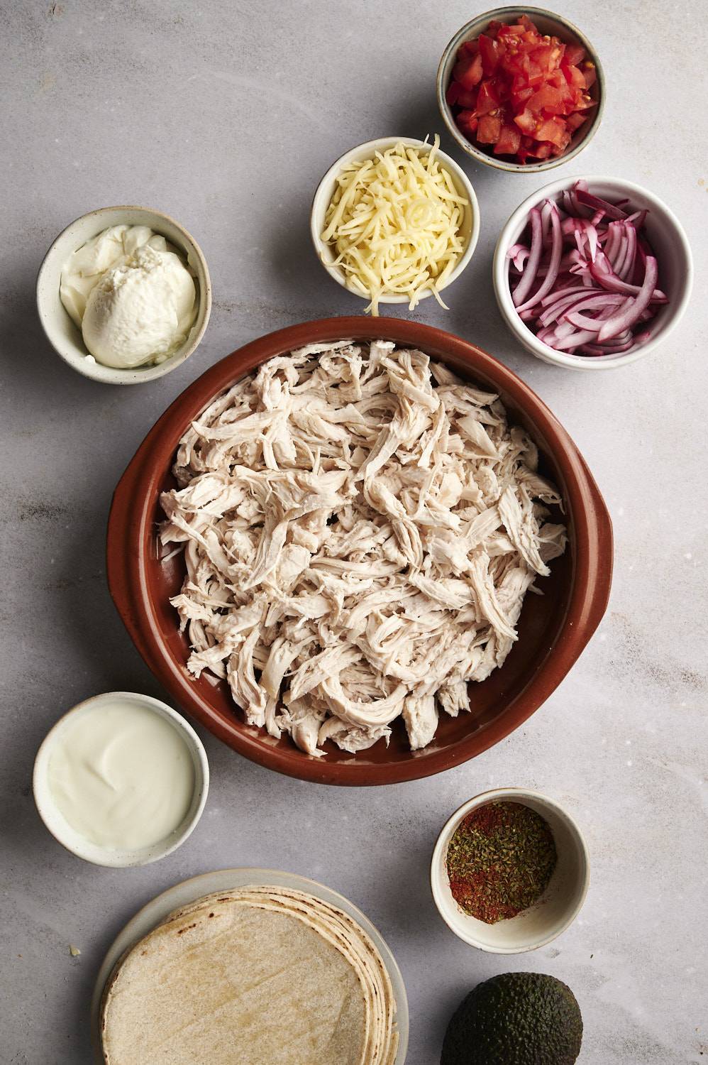 Ingredients for tacos dorados including shredded chicken, cheese, corn tortillas, taco seasoning, and sour cream.