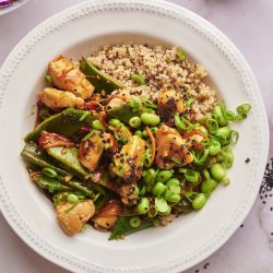 Teriyaki chicken bowls with chicken breast, snow peas, carrots, red pepper, and quinoa in a bowl with teriyaki sauce.