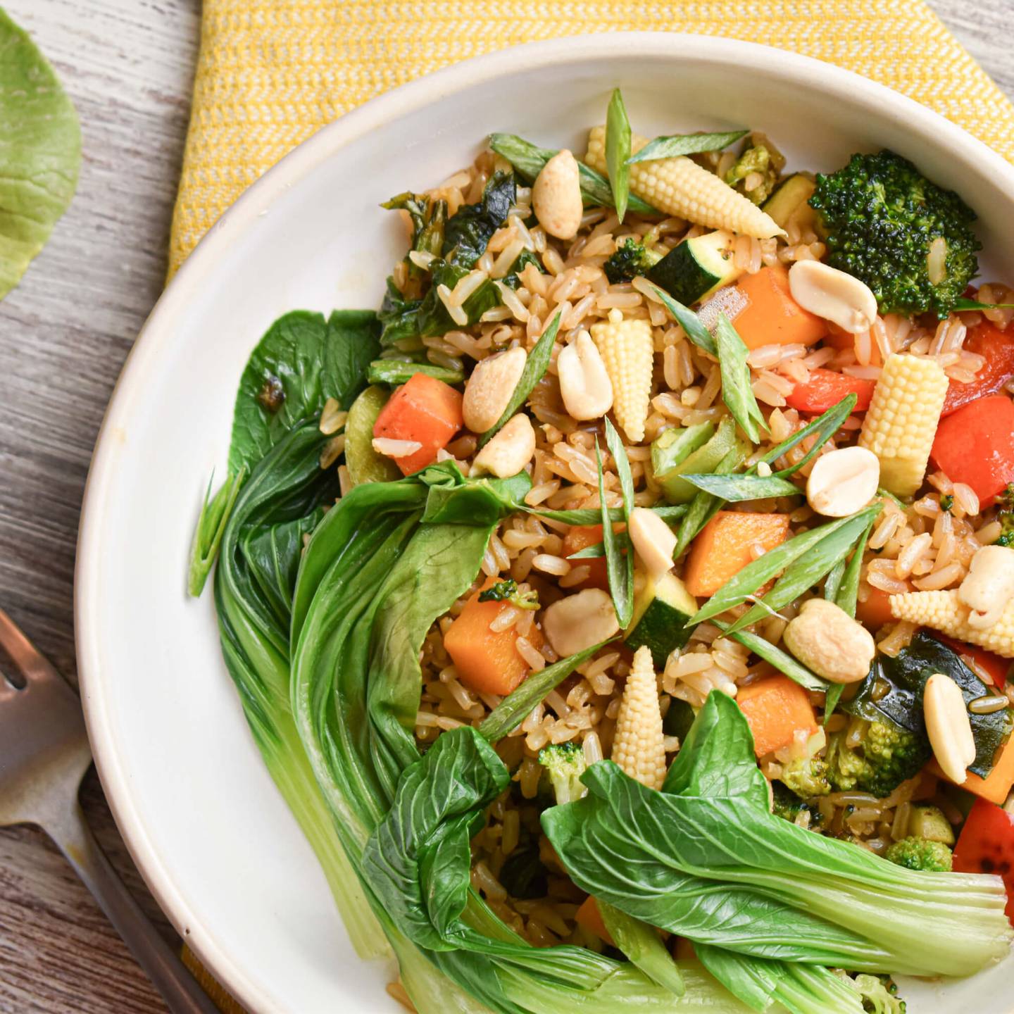 Teriyaki vegetable bowl with brown rice, bok choy, corn, edamame, carrots, and peanuts.