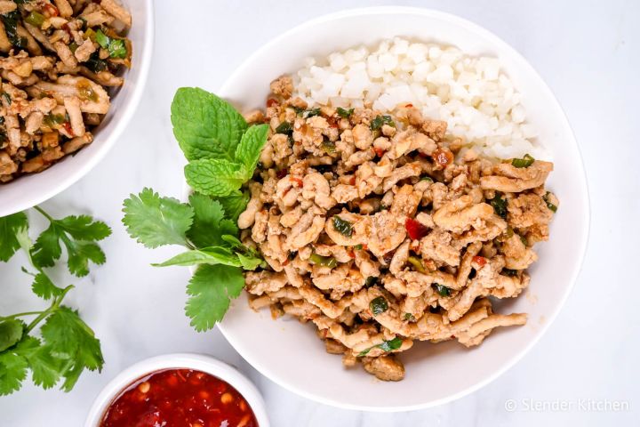 Thai Chicken Larb with fresh mint and basil in a white bowl with cauliflower rice.