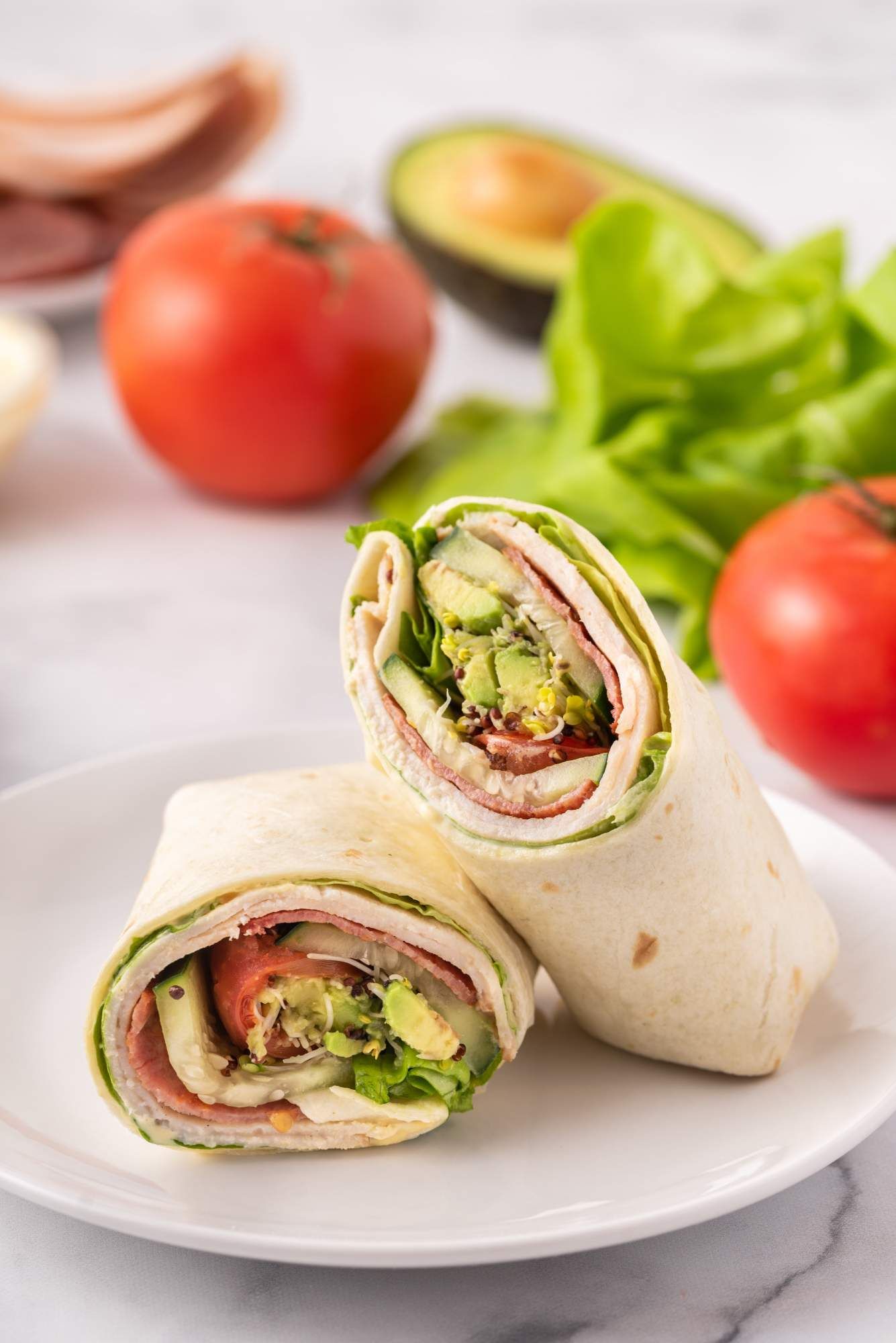 Turkey wraps with BLT fillings including bacon, turkey, avocado, tomato, and lettuce wrapped in a tortilla.