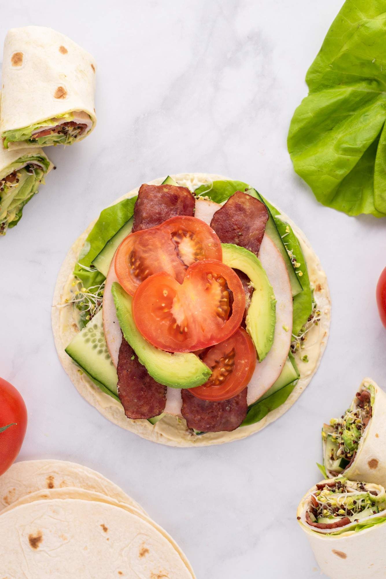 Turkey and bacon wraps with tomato, lettuce, sprouts, avocado, and a mayonnaise and mustard sauce.