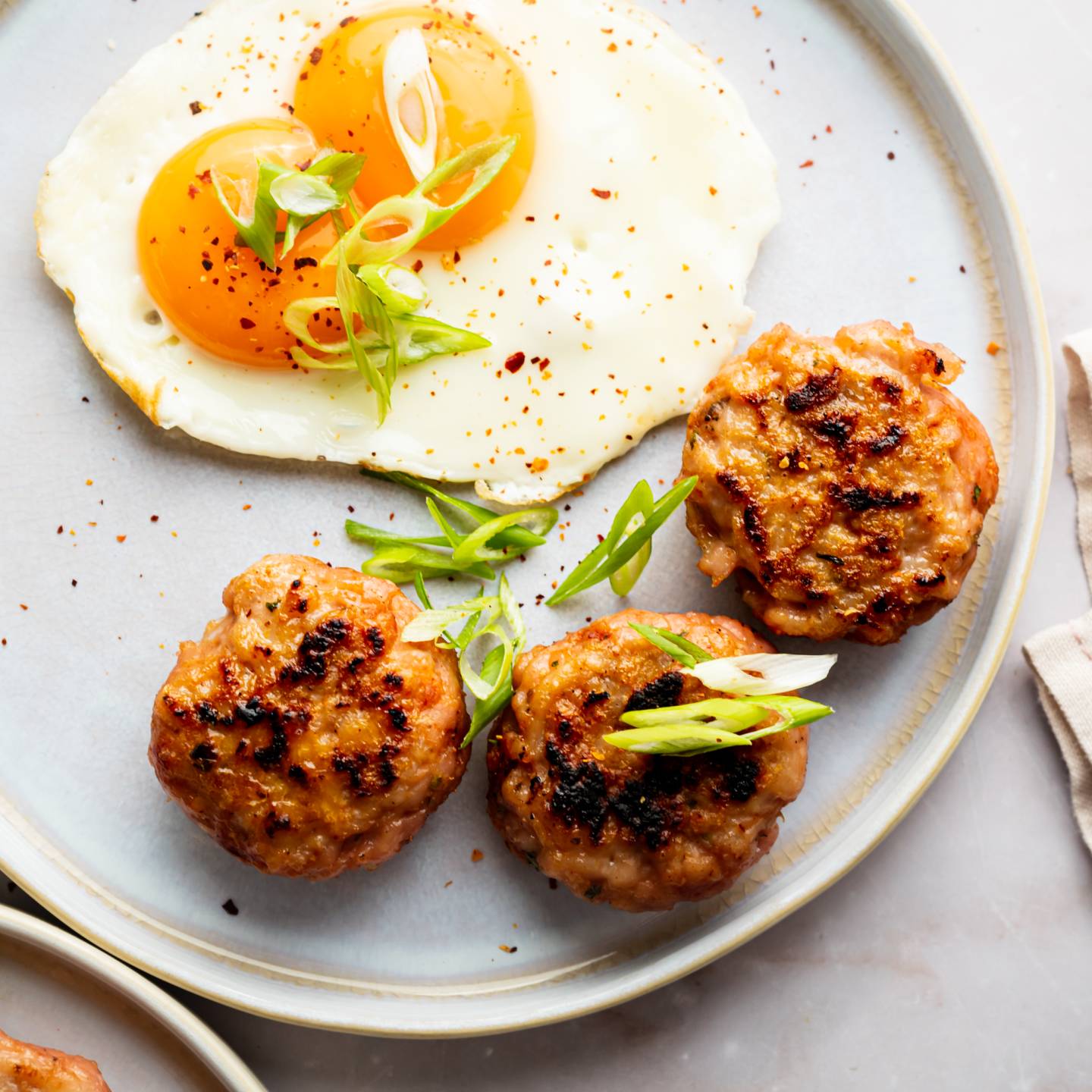 Turkey breakfast sausage served on a plate with sunny side ip eggs and green onions.