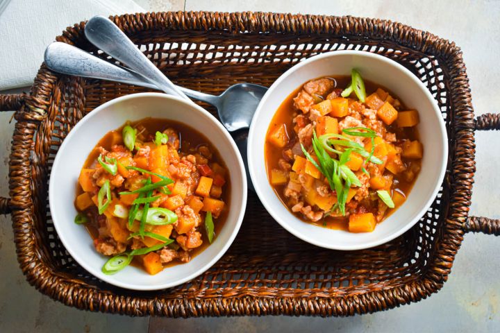 Turkey butternut squash chili with tomatoes, butternut squash, ground turkey, and sliced green onions.