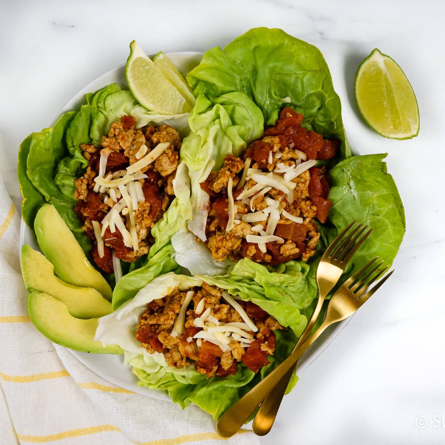 Turkey taco lettuce wraps with tomatoes, shredded cheese, ground turkey, and avocado. 