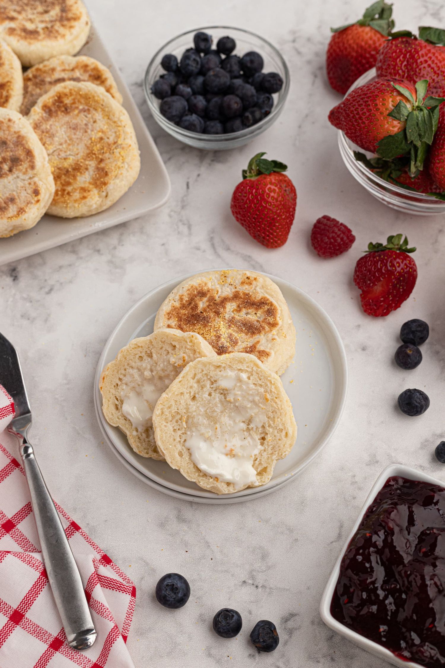 Easy English muffins made with Greek yogurt dough on a plate with butter.