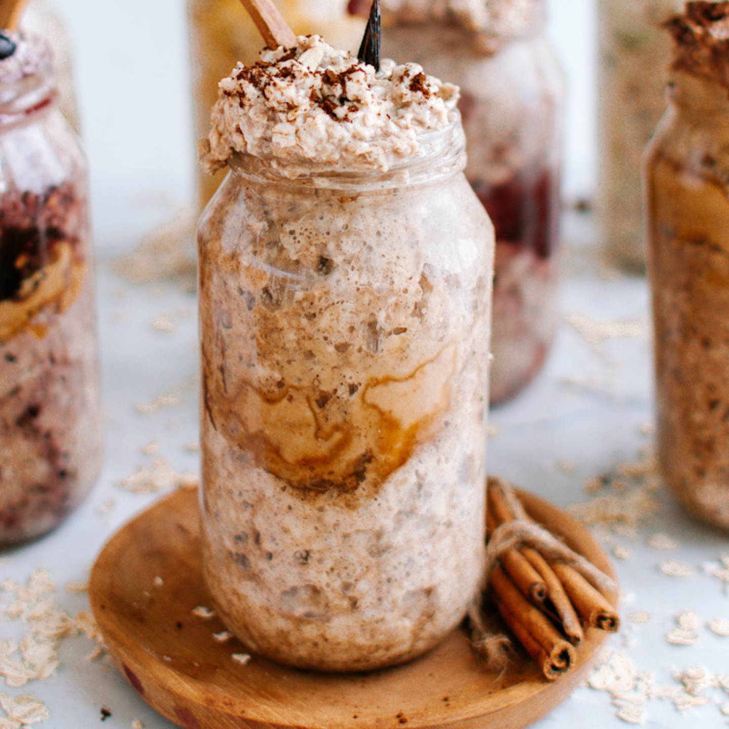 Vanilla latte overnight oatmeal with cinnamon in a glass jar with a touch of whipped cream on top.