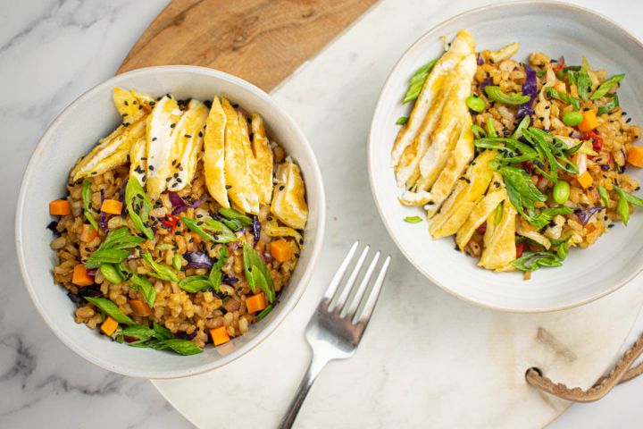 Vegetable fried rice with brown rice, eggs, carrots, peas, and cabbage in a cilantro.