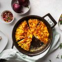 Western omelet frittata with peppers, onions, ham, and cheese cooked in a cast iron skillet and served with fresh parsley.